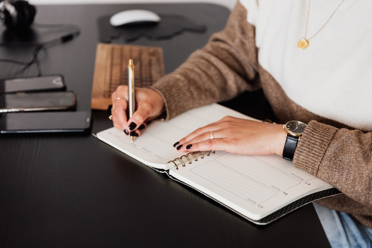 Crop stylish woman taking notes in notebook 